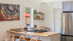 Une cuisine moderne avec un îlot central, un plancher en bois et une grande fenêtre.