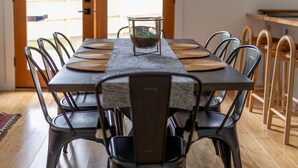 Un espace repas comprenant une table en bois, des chaises en métal et un centre de table en verre.