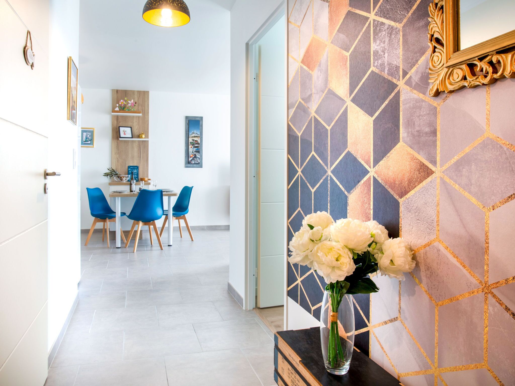 A modern interior with a dining area, a vase of flowers, and a geometric patterned wall.