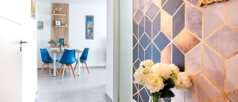 A modern interior with a dining area, a vase of flowers, and a geometric patterned wall.