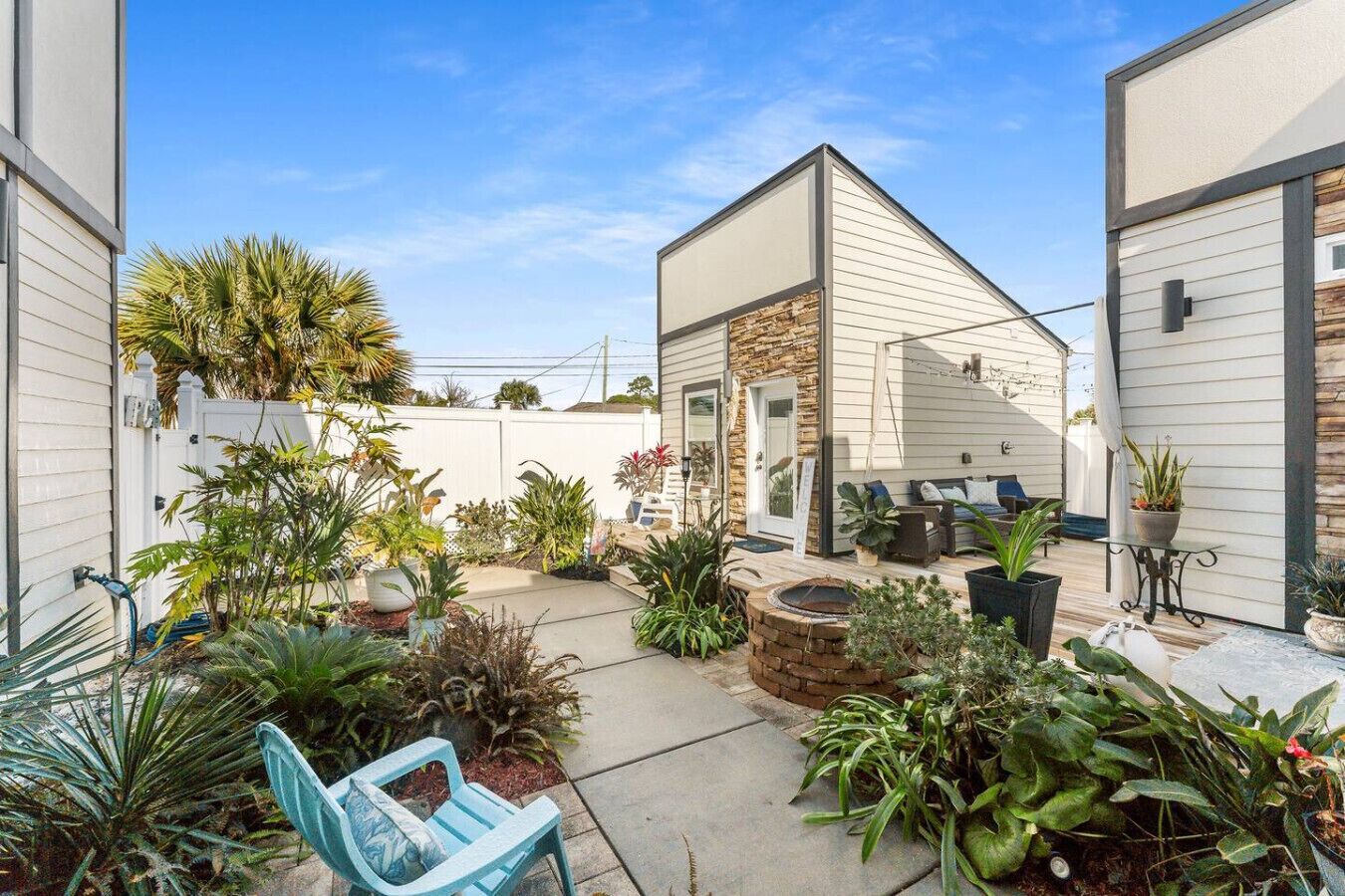 Una casa moderna con un patio que incluye mobiliario exterior, una chimenea y varias plantas.