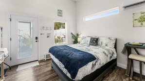 A bedroom with a bed, a desk, a window, and a door. - Hot Tub, 10min walk to Beach at Tiny Treasure (Panama City Beach)