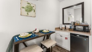 A compact kitchen with a microwave, sink, and a small dining area with stools. - Hot Tub, 10min walk to Beach at Tiny Treasure (Panama City Beach)