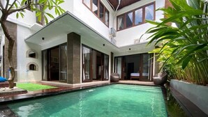 Ein modernes Haus mit Schwimmbad, großen Fenstern und einer überdachten Terrasse.