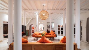 A spacious living area with a large wooden sofa set, orange cushions, and a woven pendant light. - Seminyak Villa Kubuku 4 bedrooms (Bali)