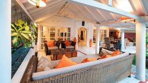 A spacious outdoor lounge area with wicker furniture, a coffee table, and orange cushions. - Seminyak Villa Kubuku 4 bedrooms (Bali)