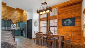 Eine geräumige Küche mit Holzwänden, eine Essecke mit einem Holztisch und -stühlen sowie eine Treppe zu einer anderen Ebene.