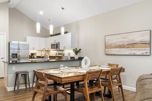 A modern kitchen with white cabinets, stainless steel appliances, and pendant lighting.