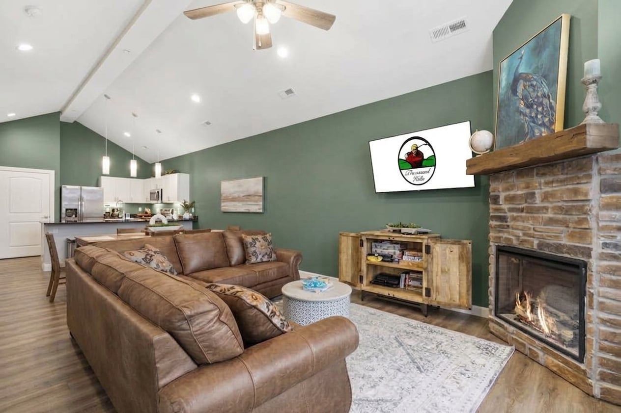 A modern living room with a sectional sofa, a fireplace, and a kitchen in the background.