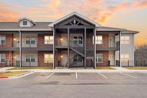 A multi-story building with a central staircase, balconies, and a parking lot.