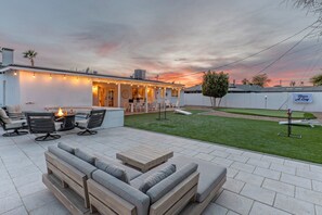A patio with outdoor furniture, a fire pit, and a well-maintained lawn.