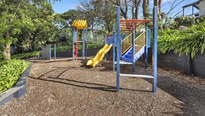 Ein Spielplatz mit einer gelben Rutsche, einer blauen Rutsche und einer Kletterkonstruktion.