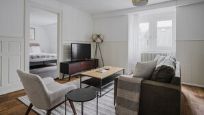 Uma sala de estar moderna com sofá, poltronas, mesa de centro, televisão e luminária de chão.