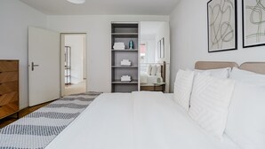 Et moderne soveværelse med en stor seng, et skab, indbyggede hylder og et natbord.