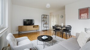 En moderne stue med fjernsyn, sofa, sofabord og spiseområde.