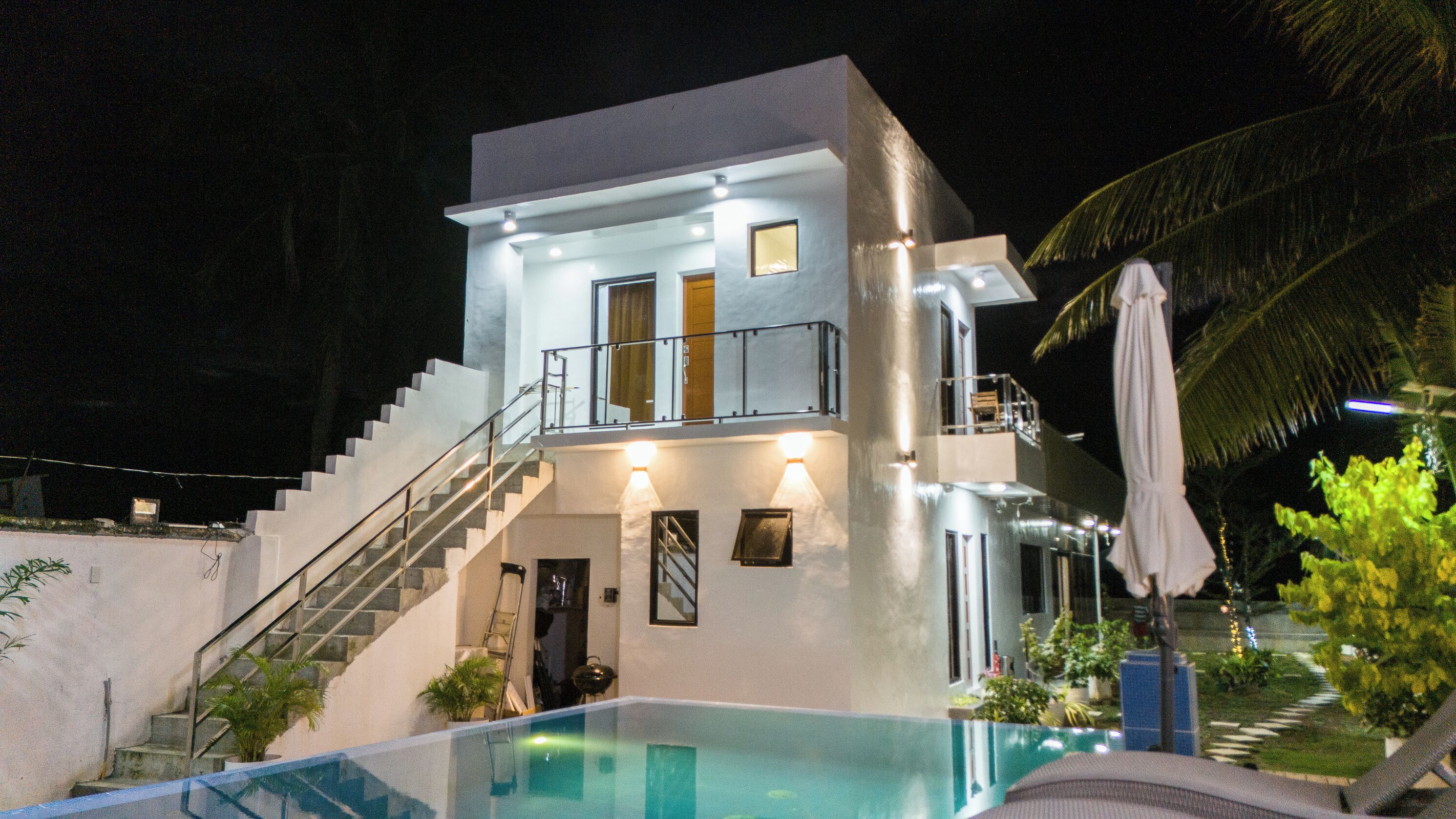 Un bâtiment moderne à deux étages, doté d’une piscine intérieure à panneaux de verre, d’un escalier et d’un balcon.