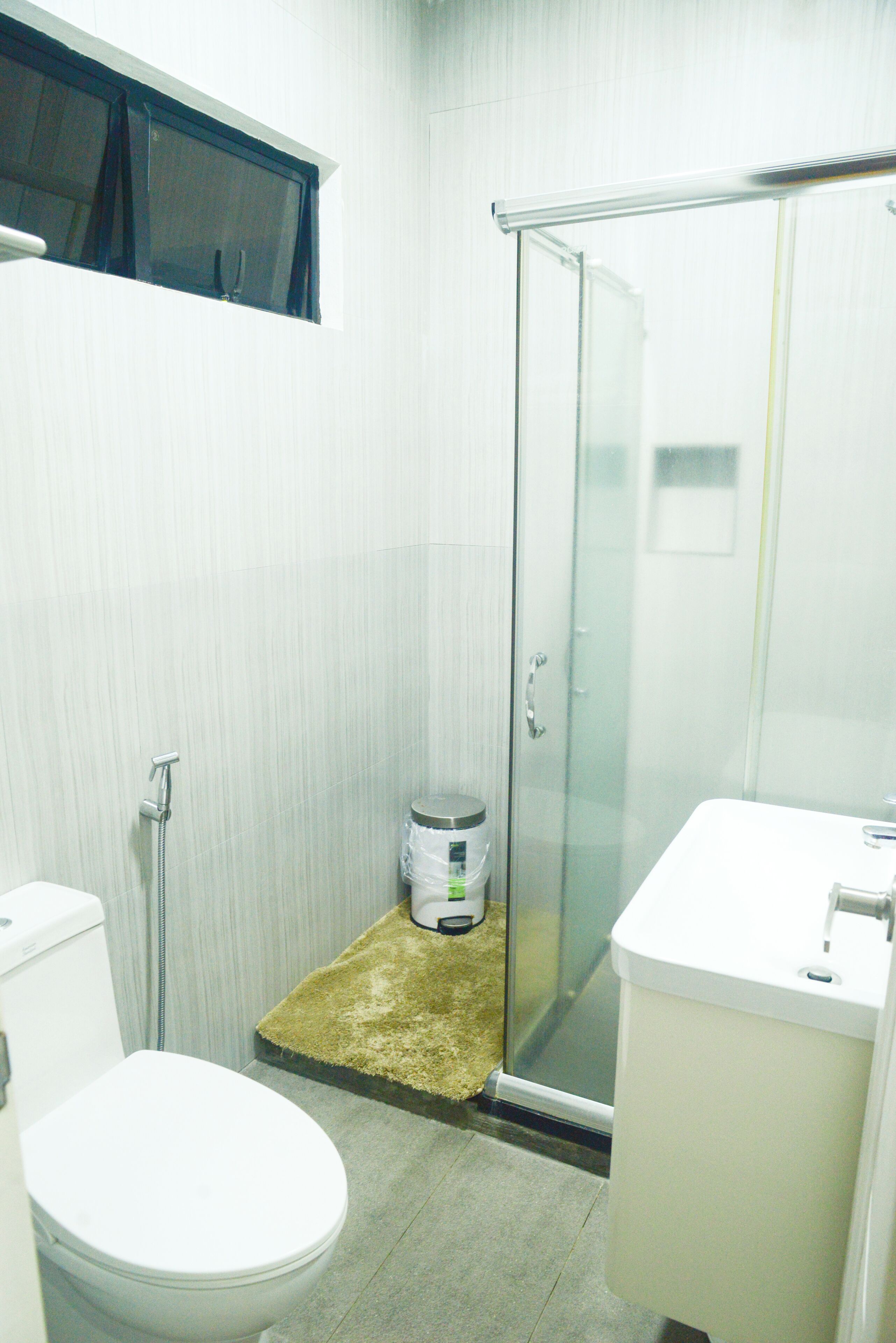 A small bathroom with a toilet, a shower, and a sink.