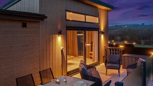 A modern building with a dining area featuring tables and chairs, large windows, and a view of the landscape. - The Duck Pond - Countryside Hot Tub (Narberth)