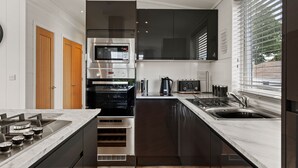 A modern kitchen with a built-in oven, microwave, and stainless steel appliances. - The Duck Pond - Countryside Hot Tub (Narberth)
