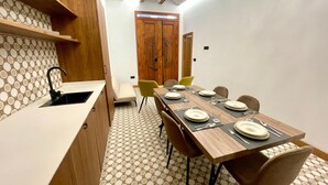 A modern kitchen with a dining area, featuring a wooden table set for four, a built-in oven, and a patterned floor. - Los Angeles With 3 Bedrooms and 3 Bathrooms (Valencia)