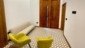 A room with a beige sofa, two yellow chairs, a wooden door with a glass panel, and a patterned floor. - Los Angeles With 3 Bedrooms and 3 Bathrooms (Valencia)