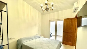 A bedroom with a bed, a chandelier, an air conditioner, and a sliding glass door leading to an outdoor area. - Los Angeles With 3 Bedrooms and 3 Bathrooms (Valencia)
