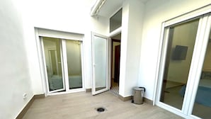 A room with a wooden floor, a sliding glass door leading to a balcony, a trash can, and a small window. - Los Angeles With 3 Bedrooms and 3 Bathrooms (Valencia)