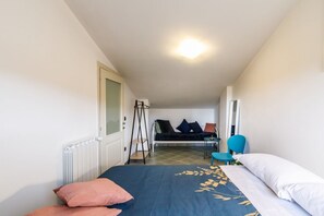 A bedroom with a bed, a chair, a small table, a radiator, and a window. - GuestHost - Comfortable 91 sqm two- floor modern flat (with internal spiral staircase), 5 min walk from the Colonna San Marco stop, which connects it to the historical centre. With two bedrooms, two bathrooms and a living room, it can accommodate 5 peopl (Siena)