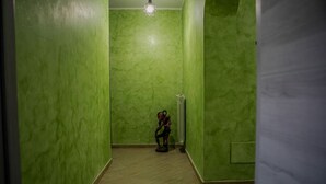Een smalle gang met groene wanden en een houten vloer.
