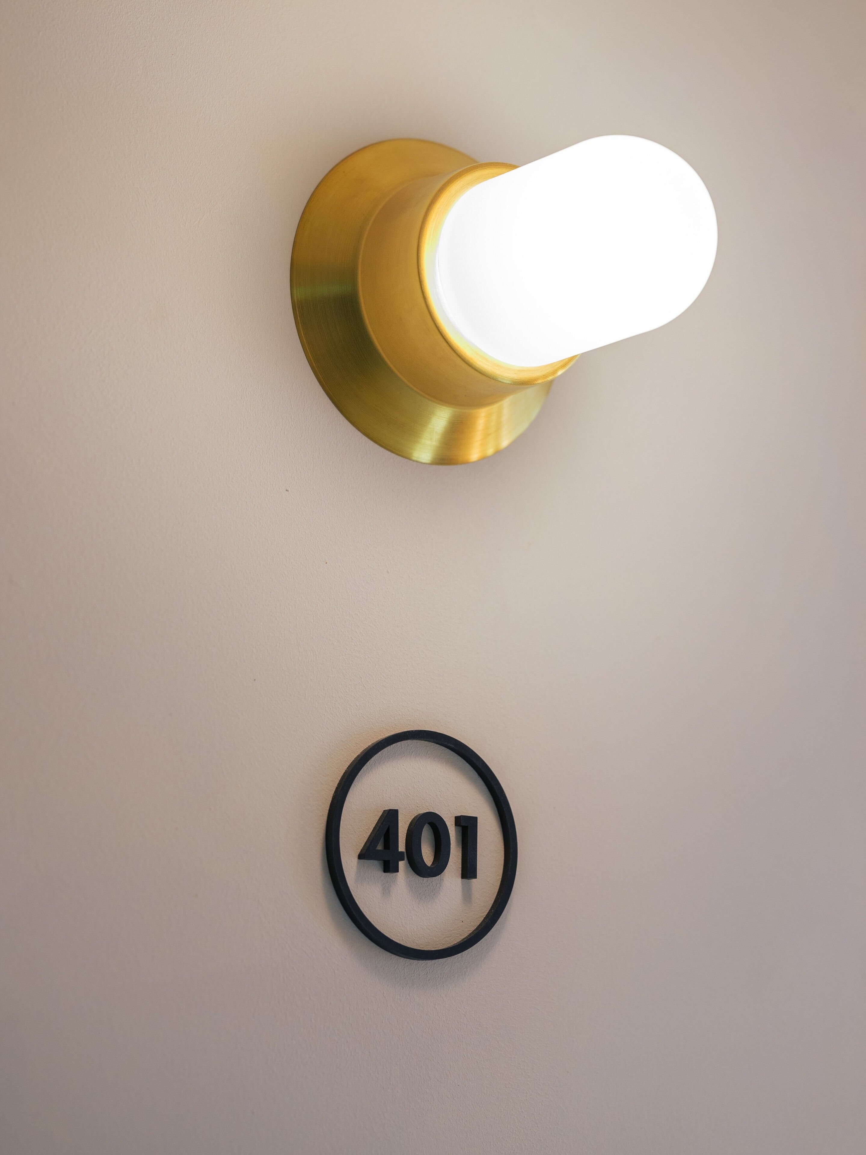 Una lámpara fijada a la pared, con interruptor y un letrero circular con el número 401.