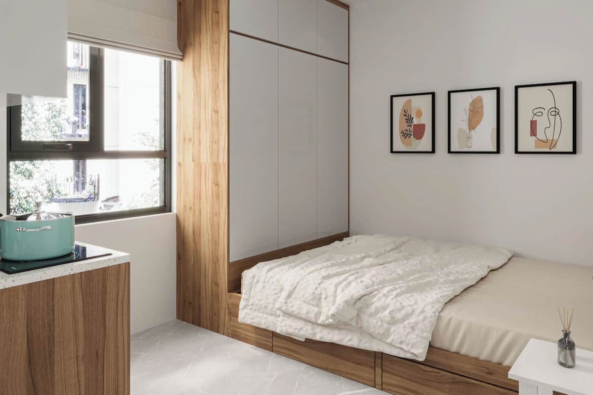 A bedroom with a bed, a wardrobe, a window, and three framed artworks on the wall.