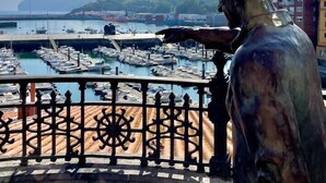 A statue overlooking a marina with boats and buildings in the background. - Ogoño apartment Bermeo (Bermeo)