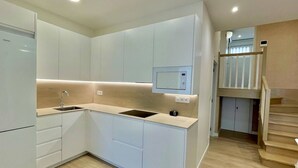 A modern kitchen with white cabinets, a built-in microwave, and a wooden countertop. - Ogoño apartment Bermeo (Bermeo)