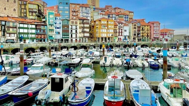 A marina with numerous boats docked, surrounded by colorful buildings and a stone bridge. - Ogoño apartment Bermeo (Bermeo)