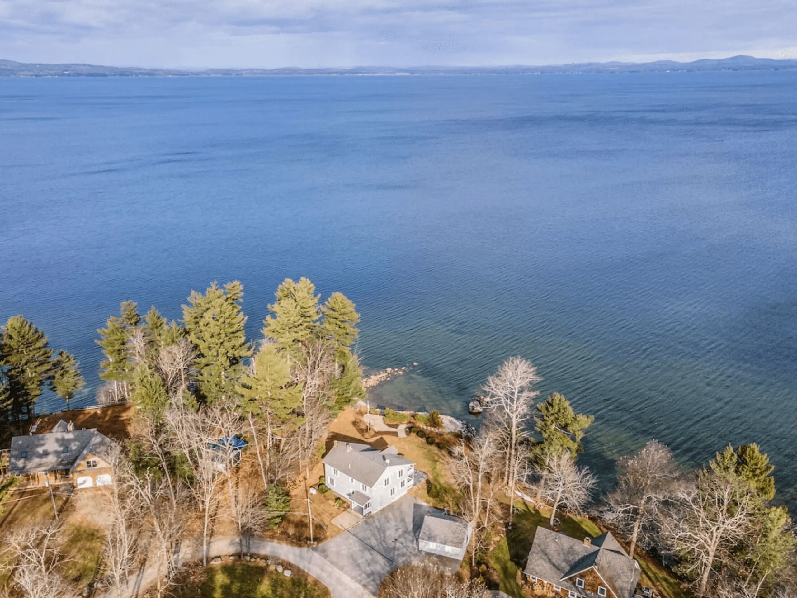 Un quartier résidentiel avec des maisons situées près d’une grande étendue d’eau, entouré d’arbres.