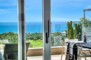 A balcony with a view of the sea, a table with chairs, and a cactus plant. - 3070 Luxury Apartment in Terrazas de Marbella, Cabopino (Marbella)