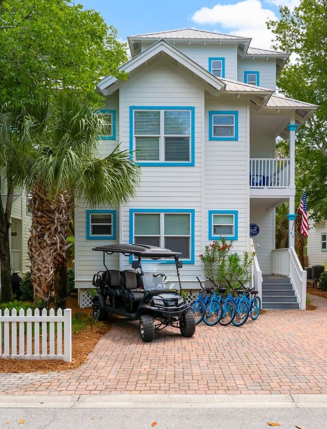 A two-story house with a porch, a golf cart, and bicycles parked in front.