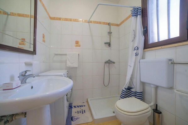 A bathroom with a sink, toilet, shower, and a mirror.