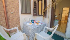 A small outdoor dining area with a table set for two, surrounded by white plastic chairs. - Marisole House With Sea View, Santa Cesarea Terme, Italy (Santa Cesarea Terme)