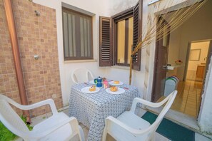 A small outdoor dining area with a table set for two, surrounded by white plastic chairs. - Marisole House With Sea View, Santa Cesarea Terme, Italy (Santa Cesarea Terme)