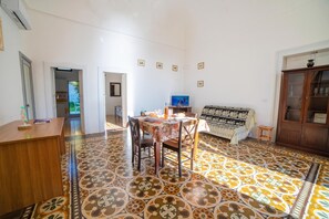 A dining area with a table and chairs, a television, and a patterned floor.
