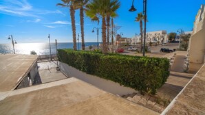 Una strada costiera con palme, cielo sereno e vista sul mare.