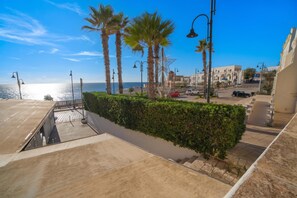A coastal street with palm trees, a clear sky, and a view of the sea. - Marisole House With Sea View, Santa Cesarea Terme, Italy (Santa Cesarea Terme)