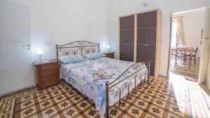 Una camera da letto con un letto, comodini, un armadio e un pavimento decorato.
