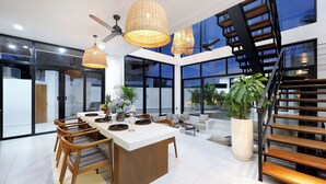 Une cuisine moderne avec un îlot central, des chaises en bois et de grandes fenêtres.
