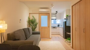 A modern living room with a sofa, a lamp, and a view into the kitchen. - Travel Time - Teradacho Noake (Osaka)