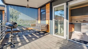 A modern outdoor patio with a grill, seating, and a view of the backyard. - Delux Eco by Interhome (Pirovac)
