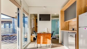 A modern kitchen with a built-in dishwasher, a dining area with a wooden table and chairs, and a view of the outside balcony. - Delux Eco by Interhome (Pirovac)