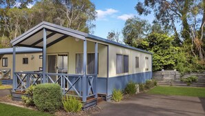 A single-story mobile home with a porch, a fenced yard, and a well-maintained lawn. - 2 Bedroom Family Villa (Metung)