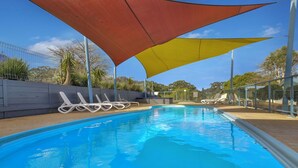 A swimming pool with lounge chairs under a shaded area. - 2 Bedroom Family Villa (Metung)